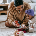 Mother playing with her infant child on carpet